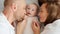 Happy family. Newborn baby with happy parents, top view. Healthy newborn baby in a white t-shirt with mom and dad. Close up Faces