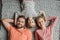 Happy family with one child lying together on grey knitted carpet