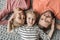 Happy family with one child lying together on grey knitted carpet