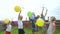 Happy family outdoors in the village waving balloons and colorful smoke