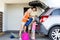 Happy family packing things to car at home parking