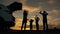 Happy family in the park. Silhouette of a happy family in the park at sunset. Parents play with their children at sunset