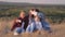 Happy family are photographed by smartphone in the park. dad, mom and daughters take a selfie in park, sitting on a