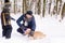 Happy family playing with a dog in snow outdoors