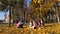 Happy family plays in the autumn park, baby wears yellow leaves for daddy. dad, mom and daughters throw yellowed leaves