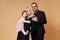 Happy family. Portrait of Mom, dad and daughter on a beige background. Beautiful couple in love holding their little daughter in