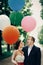 Happy family portrait, newlywed couple laughing in a sunny park in the summer, handsome groom looking at happy bride with balloons