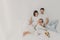 Happy family pose on white bed during weekend. Father, mother, their daughter and dog feel comfort of being in bedroom, embrace