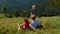 Happy family relaxing grass mountain slope. Parents lying meadow with children.