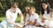 Happy family resting on the grass during a picnic in the green garden