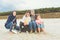 Happy family on a sandy beach - mother with three daughters sitting on a tree trunk