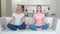 Happy family senior mother and grownup daughter on the sofa practicing yoga meditation at home. Adult woman and her