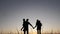 Happy family silhouette walking at sunset teamwork. Mom dad daughter and son hold hands go silhouette slow motion video