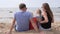 Happy Family Sits On the beach watching the sea