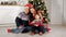 Happy family sits on floor near Christmas tree posing at set