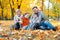 Happy family sitting on fallen leaves, playing and having fun in autumn city park. Children and parents together having a nice day