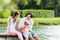 Happy family sitting on jetty on lake or pond