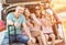 Happy family sitting on a trunk of a car with on a travel vacation