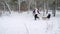 Happy family sledding on snowy winter day. Father and mother pull sled ropes with son on snowfall. Boy sledge outdoors