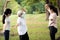 Happy family smiling while exercising at outdoor park,mother,daughter and healthy grandmother are stretching arm workout,wearing