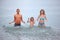 Happy family splashes water hands standing in sea