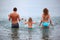 Happy family splashes water standing in sea