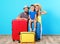 Happy family with suitcases near color wall.