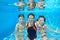 Happy family swim underwater in pool