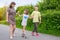 A happy family teaches a child to ride a skateboard in a park. Mom with children plays outdoors