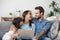 Happy family of three bonding using laptop sitting on couch