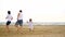 A happy family of three running around each other on a sandy sea beach, in slow motion.