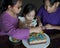 Happy family with three sibling decorating birthday cake at home.