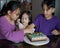 Happy family with three sibling decorating birthday cake at home.