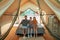 Happy family of three sitting on large bed in glamping house