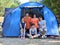 Happy family with three smiling children and tent in summer camp