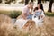 Happy family together: beautiful young parents in white clothes hugging their little daughter on straw stack in the park