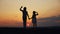 Happy family two sisters sunset walks at in the park silhouette say goodbye waving hand. two daughters. kid dream