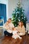 a happy family with two small children at home by the Christmas tree.