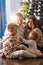 a happy family with two small children at home by the Christmas tree.