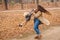 Happy family walking in autumn park. Young mother playing with son in fallen leaves. Mom spinning her toddler son. Family enjoy