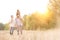 Happy family walking in wheat field with yellow lens flare in background