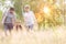 Happy family walking in wheat field with yellow lens flare in background