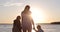 A happy family walks by the hands at the lake shore.