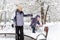 Happy family walks during snowfall in Moscow, Russia. Baby girl with mother in winter park