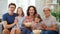 Happy family watching TV with popcorn at home.