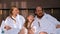 A happy family in white bathrobes sitting in the bed and talking to each other