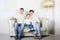 Happy family in white sweaters and jeans sit on white sofa