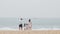 Happy family, young father and mother lift their little children holding hands together smiling on amazing sea beach.