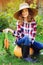 Happy farmer child girl picking fresh home growth carrot harvest from own garden