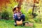 Happy farmer child girl sitting with autumn harvest in the garden